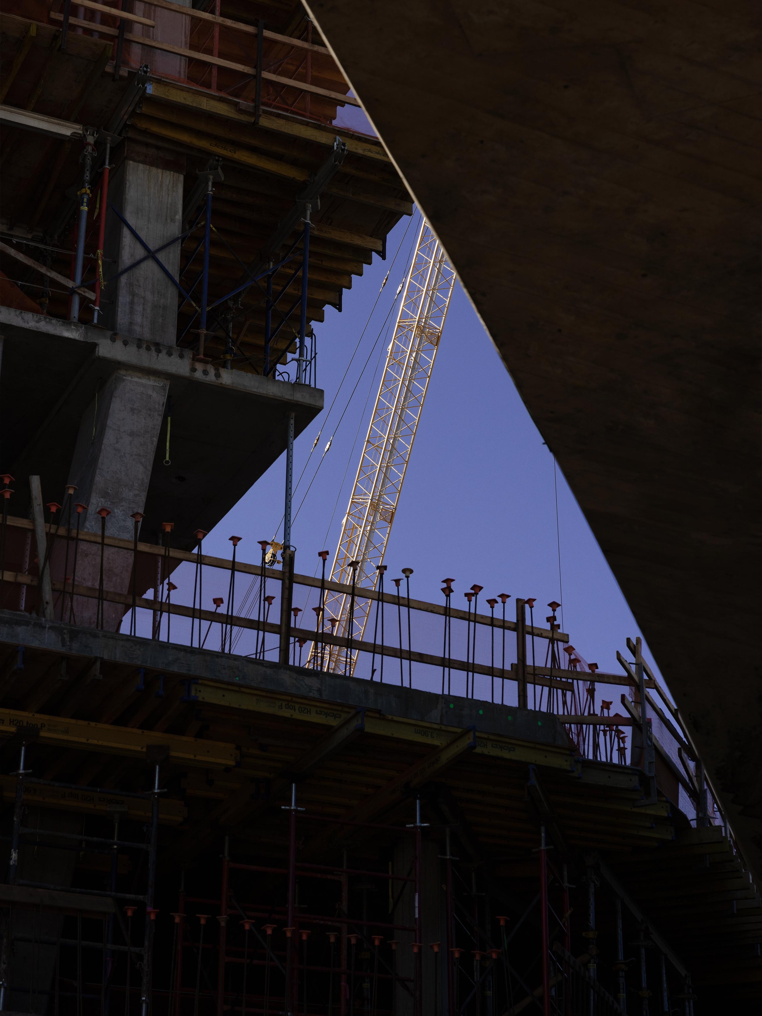 A construction crane viewed between two buildings under construction